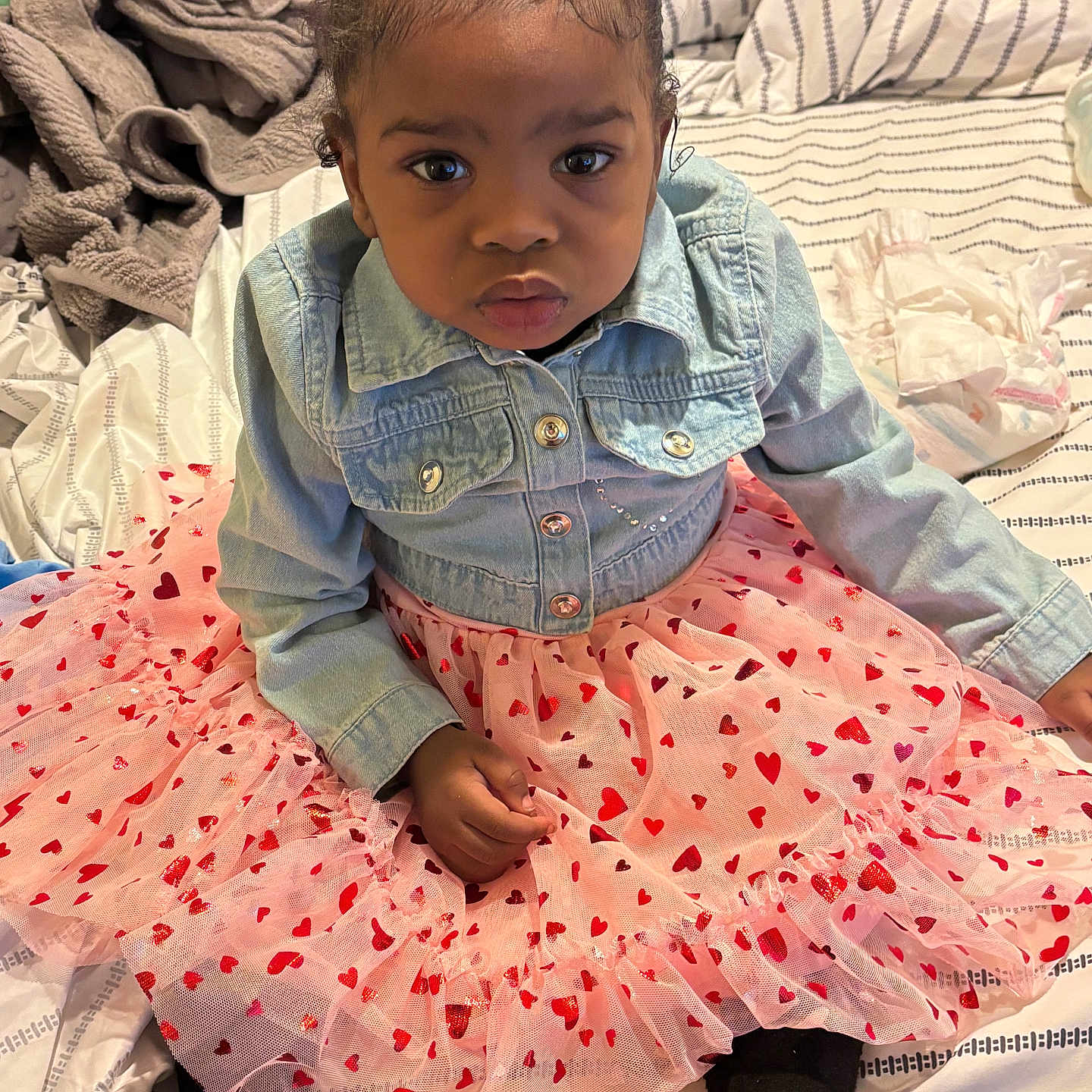 Aarionna joined the competition — help win amazing prizes! child, toddler, baby, portrait, sitting, bedroom, bed, denim_jacket, pink_dress, tutu, heart_pattern, hair_bow, red_bow, black_shoes, fashion, cute, serious_expression, indoors, bedding, photography