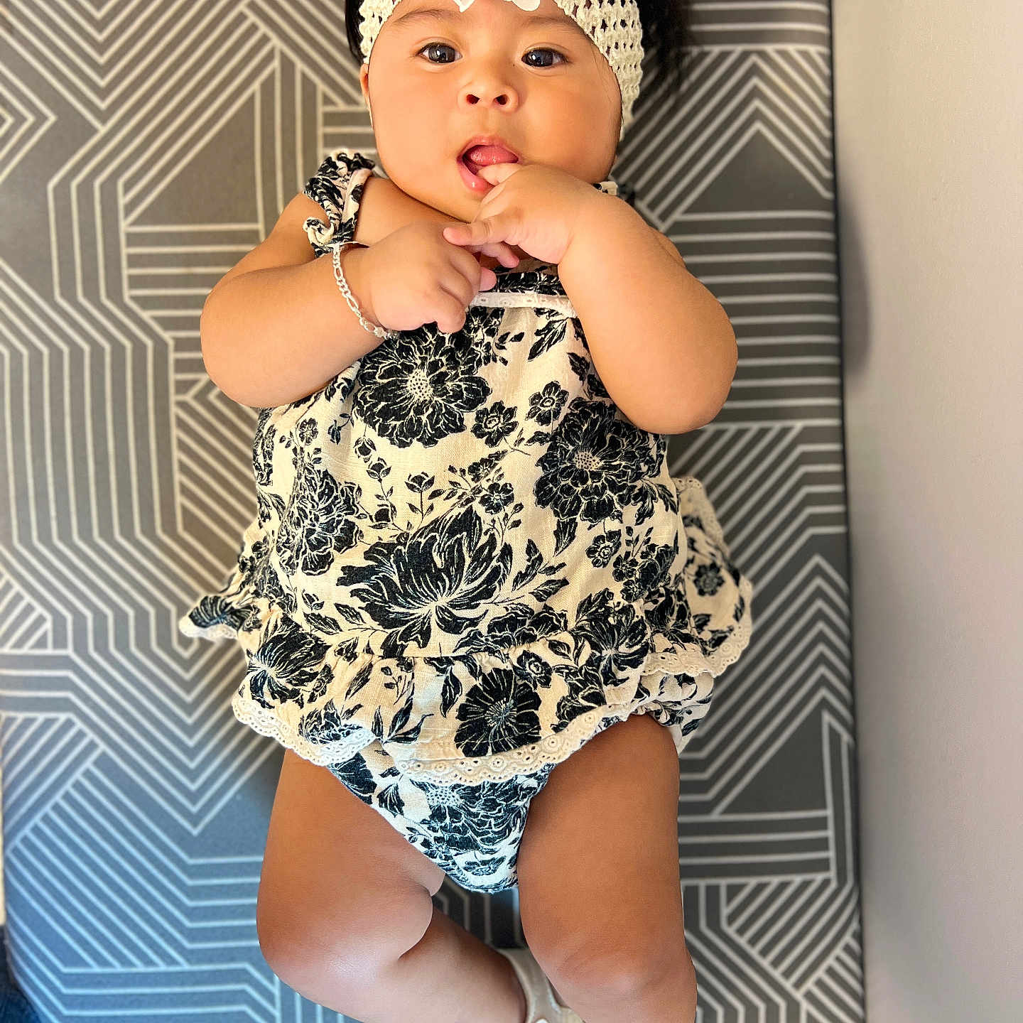 Mayvelin is registered to the contest to win money with this photo: baby, black_and_white, child, cushion, cute, expression, fingers, flower, footwear, headband, indoors, infant, lying_down, outfit, pattern, person, portrait, sandals, skin, young