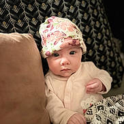 Lena participe au concours pour gagner de l'argent avec cette photo : baby, infant, hat, floral, blanket, cushion, pattern, face, clothing, person, indoors, portrait, cute, child, soft_lighting, expression, resting, cozy, newborn, lying_down
