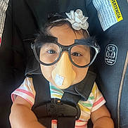 Kendra joined the competition — help win amazing prizes! baby, child, disguise, glasses, fake_nose, headband, car_seat, safety_harness, striped_shirt, smile, face, cute, indoors, funny, portrait, infant, black_straps, warning_label, seat_belt, humor