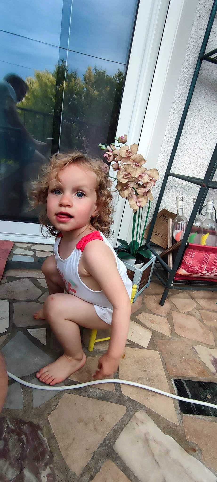 Camille participe au concours pour gagner de l'argent avec cette photo : abdomen, barefoot, blond, child, flooring, flower, foot, fun, happy, human_leg, knee, leg, leisure, person, plant, sandal, shoulder, sitting, thigh, toddler