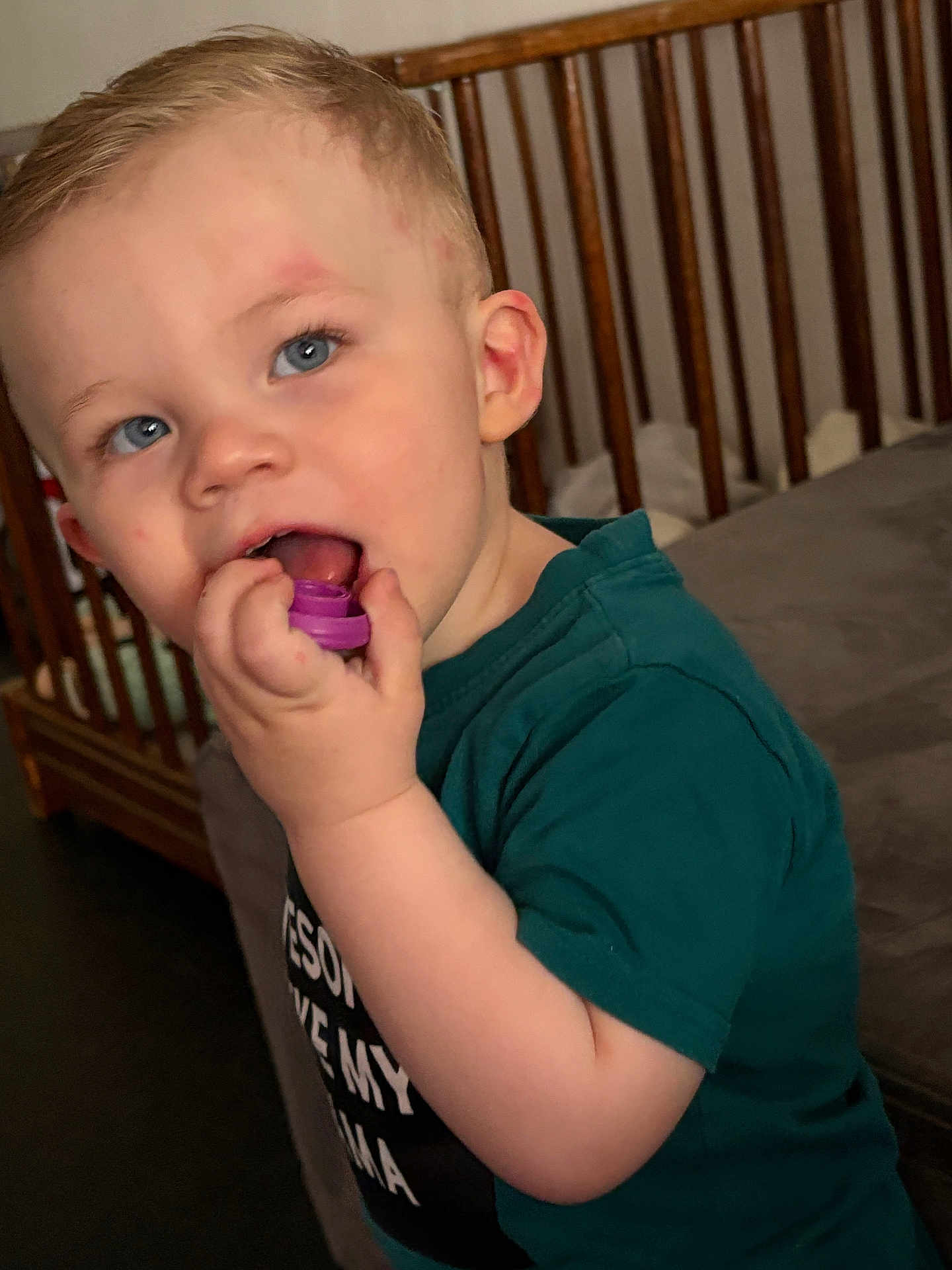 Thelyo a rejoint le concours — aidez-le/la à gagner de superbes lots ! toddler, child, blue_eyes, green_shirt, toy, hand, crib, wooden_crib, indoor, curious, face, person, young_child, short_hair, skin, chewing, closeup, standing, casual_clothing, home
