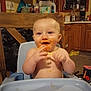 Jordyn joined the competition — help win amazing prizes! baby, high_chair, messy, food, smiling, kitchen, wooden_chair, cabinet, utensils, countertop, window, plastic_container, happy, infant, indoor, person, cute, child, face, feeding