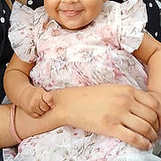 Sienna is registered to the contest to win money with this photo: baby, child, smiling, person, face, arms, clothing, dress, floral_pattern, tights, white, cute, happy, indoor, holding, portrait, infant, closeup, pattern, fabric