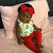 Caylee joined the competition — help win amazing prizes! baby, child, colorful_clothing, cozy, curly_hair, cute, floral_pattern, happy, headband, indoor, infant, person, pillow, pink_bed, portrait, red_bow, red_pants, relaxed, smiling, soft_fabric