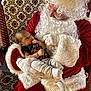Quentin is registered to the contest to win money with this photo: baby, santa_claus, child, christmas, holiday, festive, costume, beard, gloves, chair, patterned, red_clothing, white_fur, portrait, indoor, cute, holding, infant, celebration, smiling