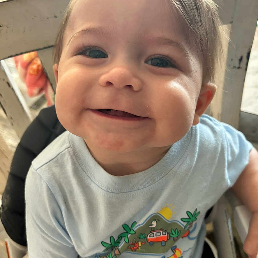 Kolby is registered to the contest to win money with this photo: baby, cartoon, child, closeup, clothing, cute, expression, face, happy, high_chair, illustration, indoor, light, person, portrait, shirt, sitting, smiling, toddler, wooden_chair