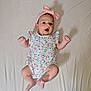 baby, infant, child, onesie, headband, pink, floral, pattern, lying_down, sheet, arms, legs, barefoot, cute, expression, indoors, skin, face, person, young