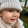 Haruto is registered to the contest to win money with this photo: baby, child, face, smile, hat, knit_hat, clothing, jacket, outdoor, nature, greenery, house, button, closeup, portrait, happy, skin, cheek, person, winter