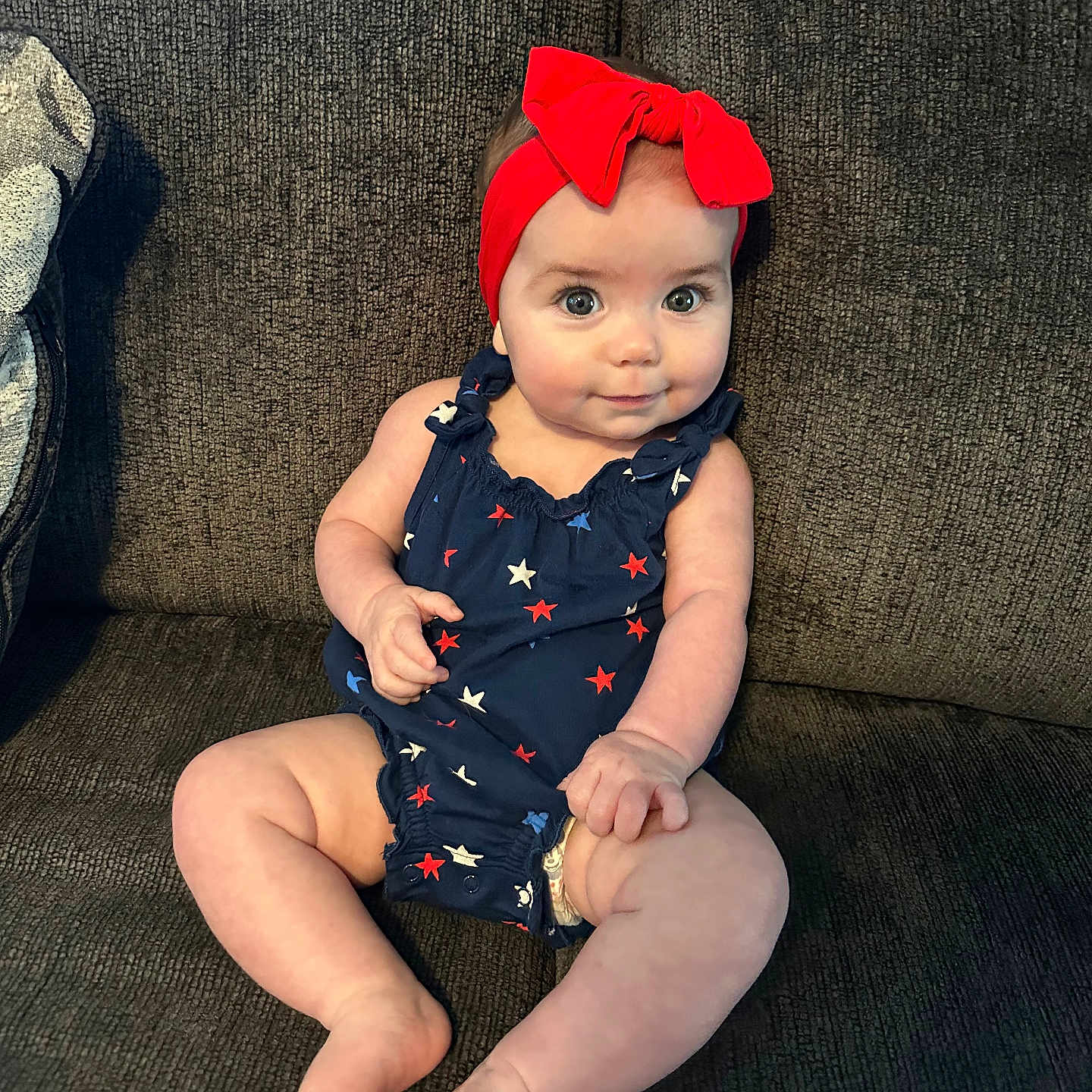 Alana is registered to the contest to win money with this photo: accessories, baby, baseballcap, bodypart, cap, clothing, couch, dress, face, finger, furniture, hat, head, headband, pants, person, photography, portrait, sitting, sleeve