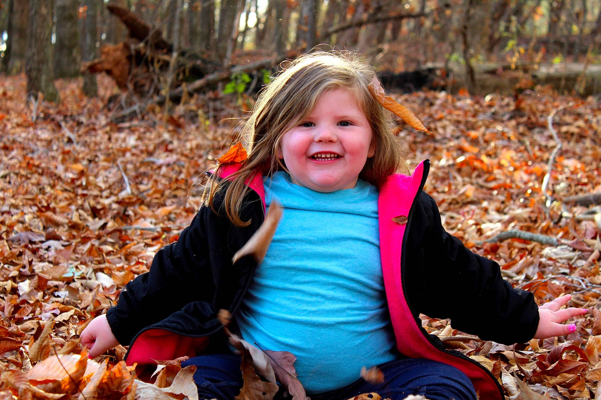 Tinsley Asta is registered to the contest to win money with this photo: child, eye, facial_expression, fun, grass, hair, happy, head, jacket, joy, leaf, leisure, people_in_nature, person, plant, recreation, smile, sunlight, toddler, tree