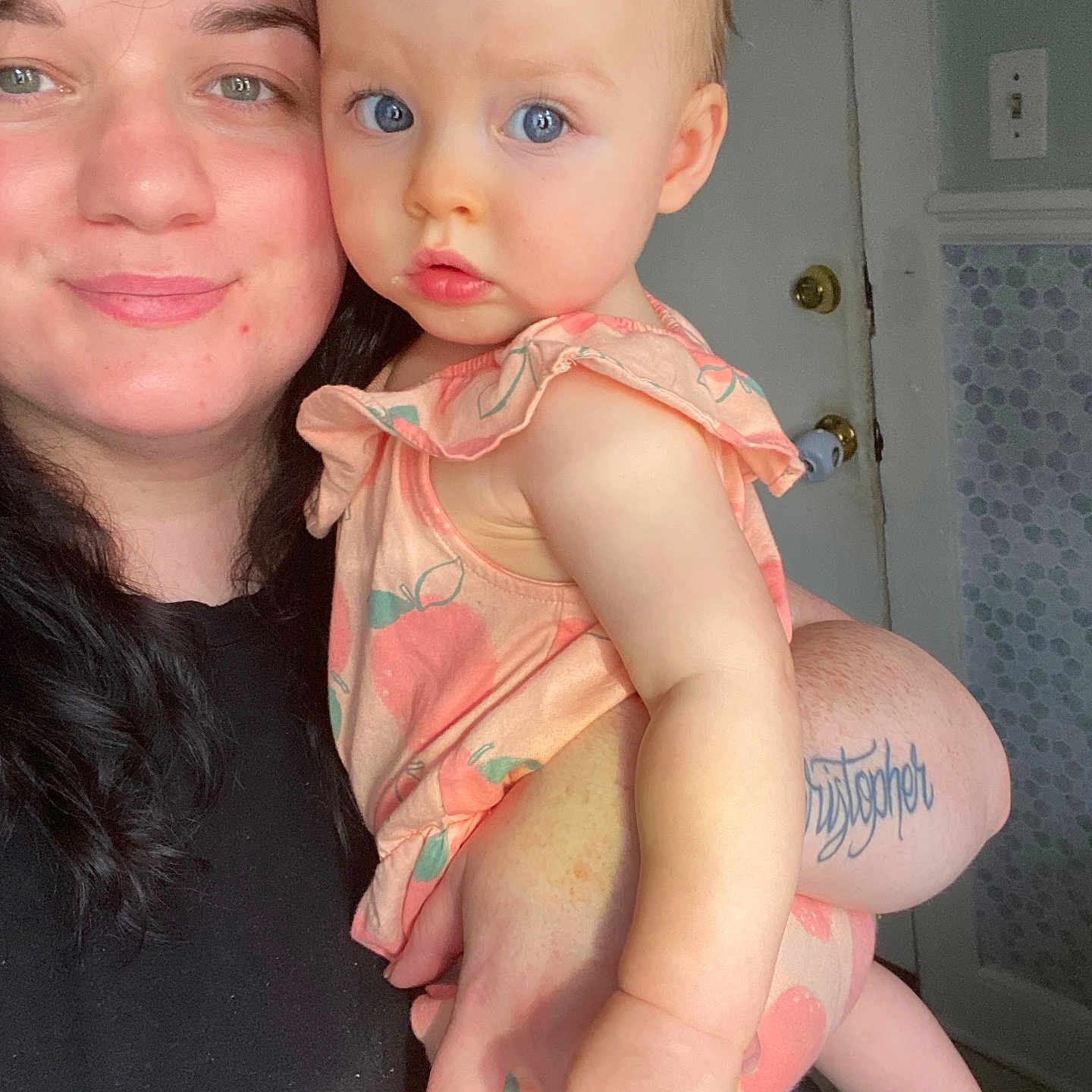 Emily is registered to the contest to win money with this photo: arm, baby, casual, child, clothing, curious, door, expression, face, hair, hand, holding, indoor, light, person, portrait, skin, smile, tattoo, woman