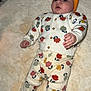 baby, infant, child, headband, bow, floral_clothing, sweater, pants, patterned_clothing, lying_down, rug, soft_texture, indoors, cute, small_hands, small_feet, looking_up, colorful, comfortable, cozy