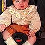 baby, child, car_seat, headband, bow, socks, clothing, floral, bib, cute, infant, sitting, portrait, indoors, face, hands, legs, footwear, safety, expression