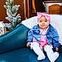 baby, child, infant, denim_jacket, pink_bow, white_socks, couch, blue_eyes, holiday_decor, frosted_tree, lantern, cozy, cute, indoor, portrait, smiling, sitting, pink_outfit, decorative_bucket, festive_pillow
