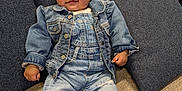 Xenia is registered to the contest to win money with this photo: baby, carpet, child, cozy, cushion, cute, denim_jacket, denim_overalls, feet, furniture, hand, indoors, living_room, pillow, portrait, sitting, smile, socks, sofa, window