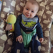 George joined the competition — help win amazing prizes! animal_print, baby, bib, blue_sweater, bunny_pattern, chair, child, clothing, comfort, cushion, cute, face, hand, indoor, infant, pants, portrait, seatbelt, smiling, toy