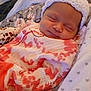 Leah joined the competition — help win amazing prizes! baby, sleeping, knitted_hat, onesie, plush_toy, giraffe_toy, blanket, cozy, infant, peaceful, child, soft_lighting, indoors, portrait, cute, smiling, resting, headwear, fabric, person