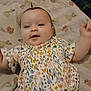 baby, child, infant, smile, face, floral_dress, blanket, pattern, happy, cute, person, young_child, lying_down, indoor, skin, head, hair, clothing, baby_girl, motion_blur