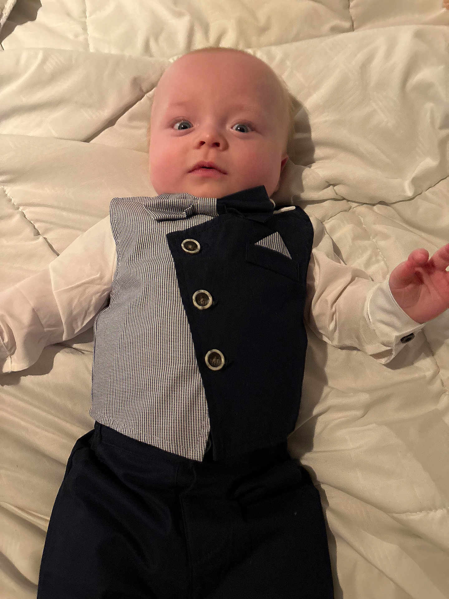 Richard joined the competition — help win amazing prizes! baby, infant, tuxedo, bow_tie, vest, clothing, white_shirt, lying_down, blanket, quilt, bed, cute, face, portrait, child, young, expression, hands, indoors, person