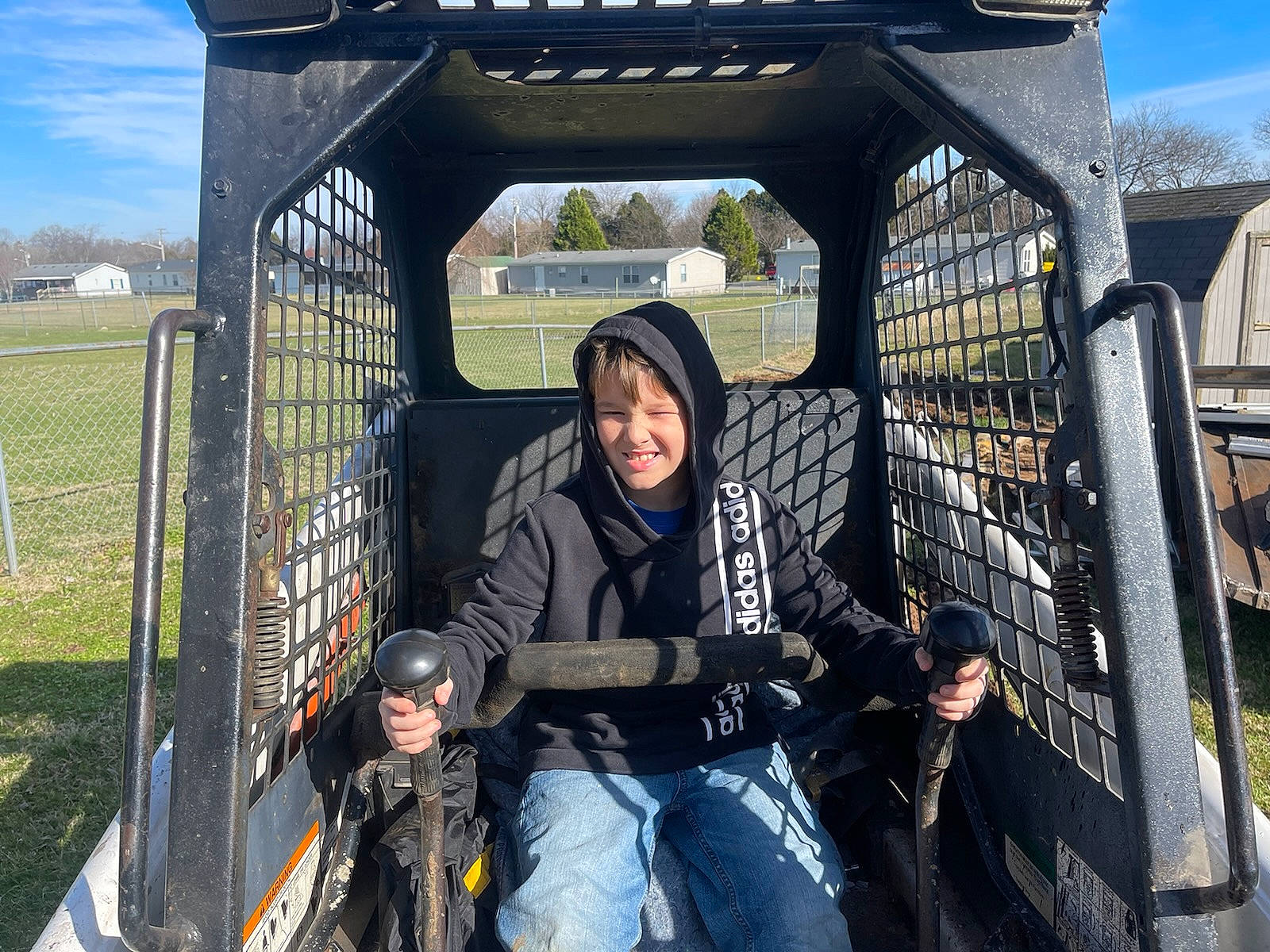 Peyton is registered to the contest to win money with this photo: automotive_exterior, automotive_tire, automotive_wheel_system, fence, fun, grass, jacket, jeans, joy, landscape, leisure, motor_vehicle, person, recreation, sitting, sky, smile, t_shirt, travel, tree
