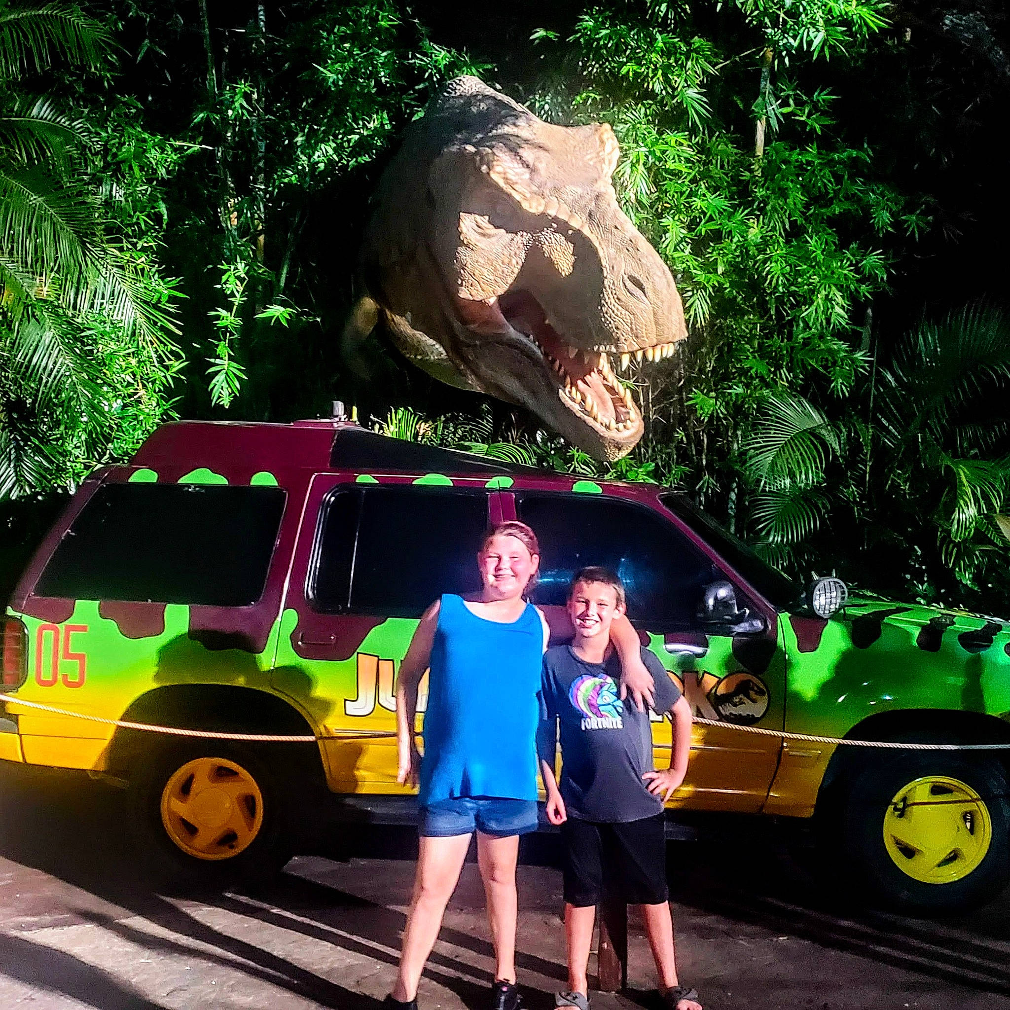 Peyton is registered to the contest to win money with this photo: asphalt, automotive_design, automotive_exterior, automotive_lighting, automotive_tire, car, green, joy, mammal, mode_of_transport, motor_vehicle, natural_environment, organism, person, road, shorts, tire, travel, tree, vehicle