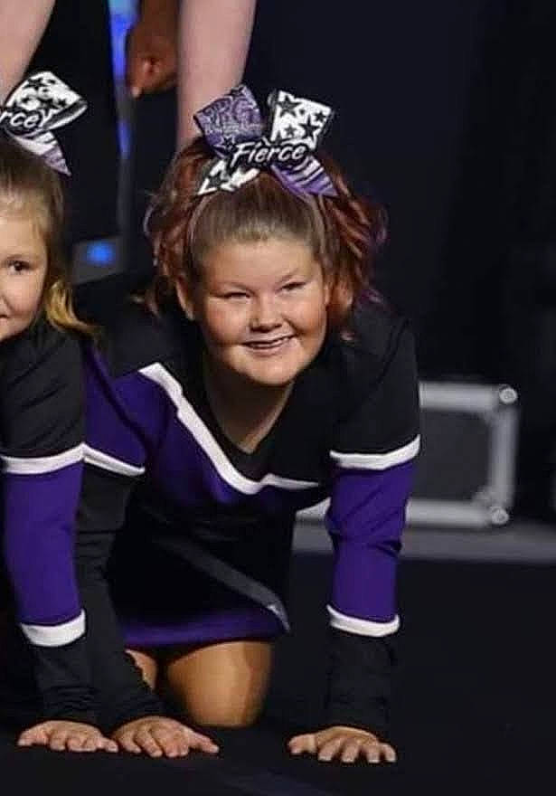 Kaylee is registered to the contest to win money with this photo: cheerleading, cheerleading_uniform, child, dance, electric_blue, entertainment, event, face, fashion_accessory, fun, happy, headpiece, jewellery, joy, performing_arts, person, purple, smile, sports_uniform, sportswear