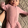baby, infant, pink_onesie, blanket, hand, tattoo, face, person, lying_down, clothing, texture, bed, cute, newborn, portrait, child, sleepwear, soft, indoor, expression