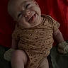 baby, infant, smiling, tongue_out, onesie, leopard_print, lying_down, red_background, cute, playful, child, sock, mittens, happy, portrait, skin, expression, person, indoor, young