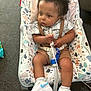 Lafenis Owens joined the competition — help win amazing prizes! toddler, child, baby_chair, medical_device, sneakers, clothing, hair, face, legs, socks, indoor, carpet, patterned_fabric, white_shoes, blue_swoosh, holding, seated, expression, curious, casual_wear