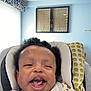 Lafenis Owens is registered to the contest to win money with this photo: baby, child, smiling, curly_hair, cushion, seat, indoor, pillow, pattern, happy, face, infant, person, light, window, walls, room, comfortable, expression, cute