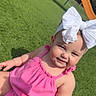 baby, child, girl, outdoor, playground, grass, pink_clothing, headband, white_bow, smiling, sunlight, happy, cute, infant, summer, play, park, young_child, person, nature