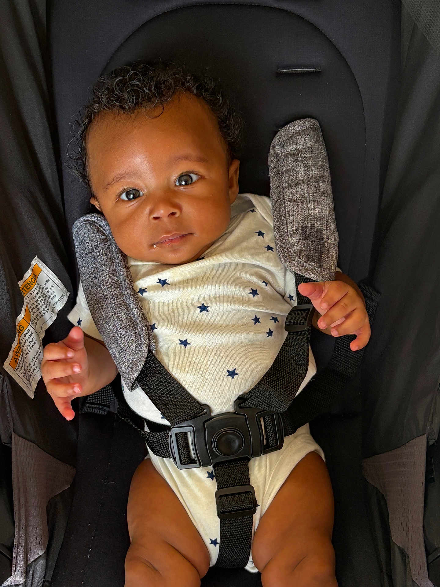 Raiden joined the competition — help win amazing prizes! baby, infant, car_seat, onesie, star_pattern, face, eyes, hands, straps, safety, child, cute, drool, clothing, seat, fabric, portrait, indoor, person, young