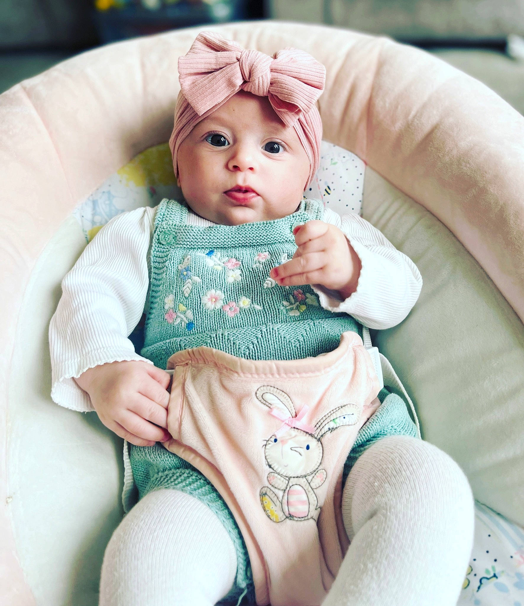 Ella is registered to the contest to win money with this photo: baby, baby_products, baby_toddler_clothing, cap, cheek, child, comfort, eye, facial_expression, finger, head, headwear, human_body, human_leg, linens, person, pink, skin, sleeve, textile