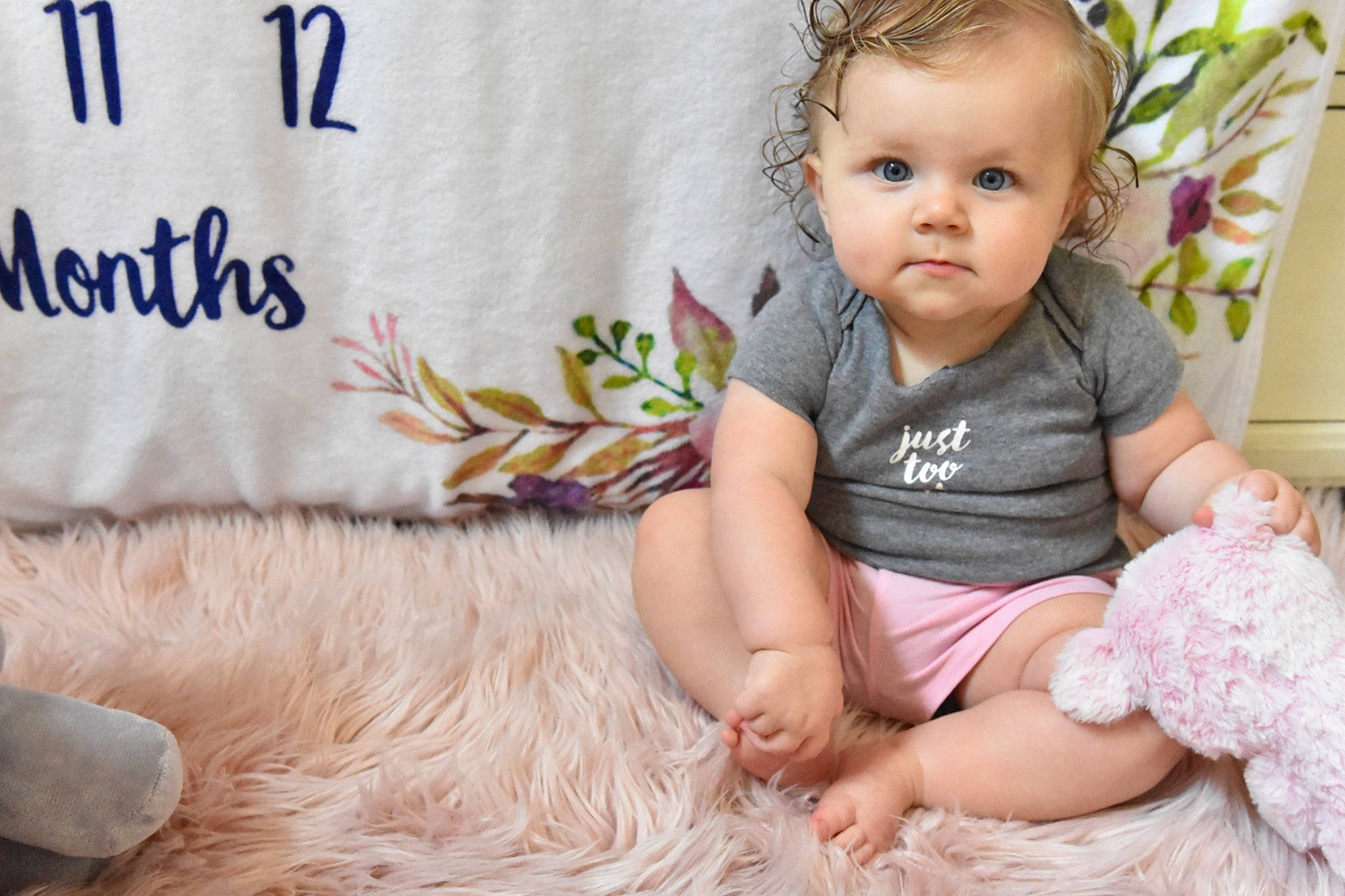 Sloane is registered to the contest to win money with this photo: baby, baby_toddler_clothing, comfort, facial_expression, finger, flooring, grass, happy, human, linens, pattern, person, pink, product, skin, sleeve, sock, t_shirt, textile, toddler