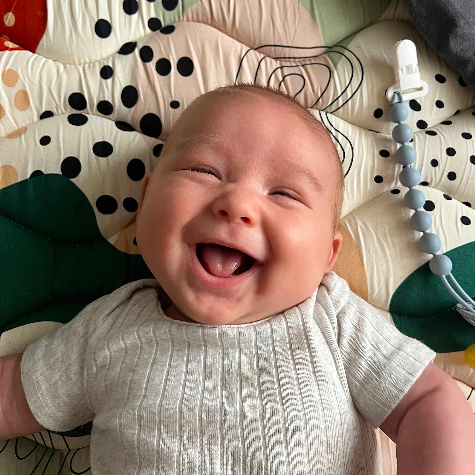 Rowan joined the competition — help win amazing prizes! baby, smiling, infant, play_mat, clothing, happy, cute, child, face, head, skin, joy, lying_down, patterned_background, white_shirt, indoors, human, young_child, expression, cheerful