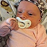 animal_print, baby, baby_clothes, blanket, calm, child, cozy, cute, headband, indoor, infant, leopard_print, lion_pattern, lying_down, newborn, pacifier, pink_sweater, portrait, sleepy, soft_texture