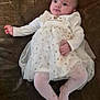 baby, infant, white_dress, golden_stars, pink_tights, lying_down, brown_background, cute, child, portrait, clothing, young_child, hands, feet, face, expression, indoors, soft_lighting, fabric, tulle