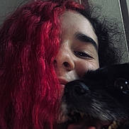Milly is registered to the contest to win money with this photo: person, dog, red_hair, black_dog, close_up, tongue_out, smile, happy, indoor, portrait, face, hair, pet, animal, cute, friendship, fun, cozy, casual, warm