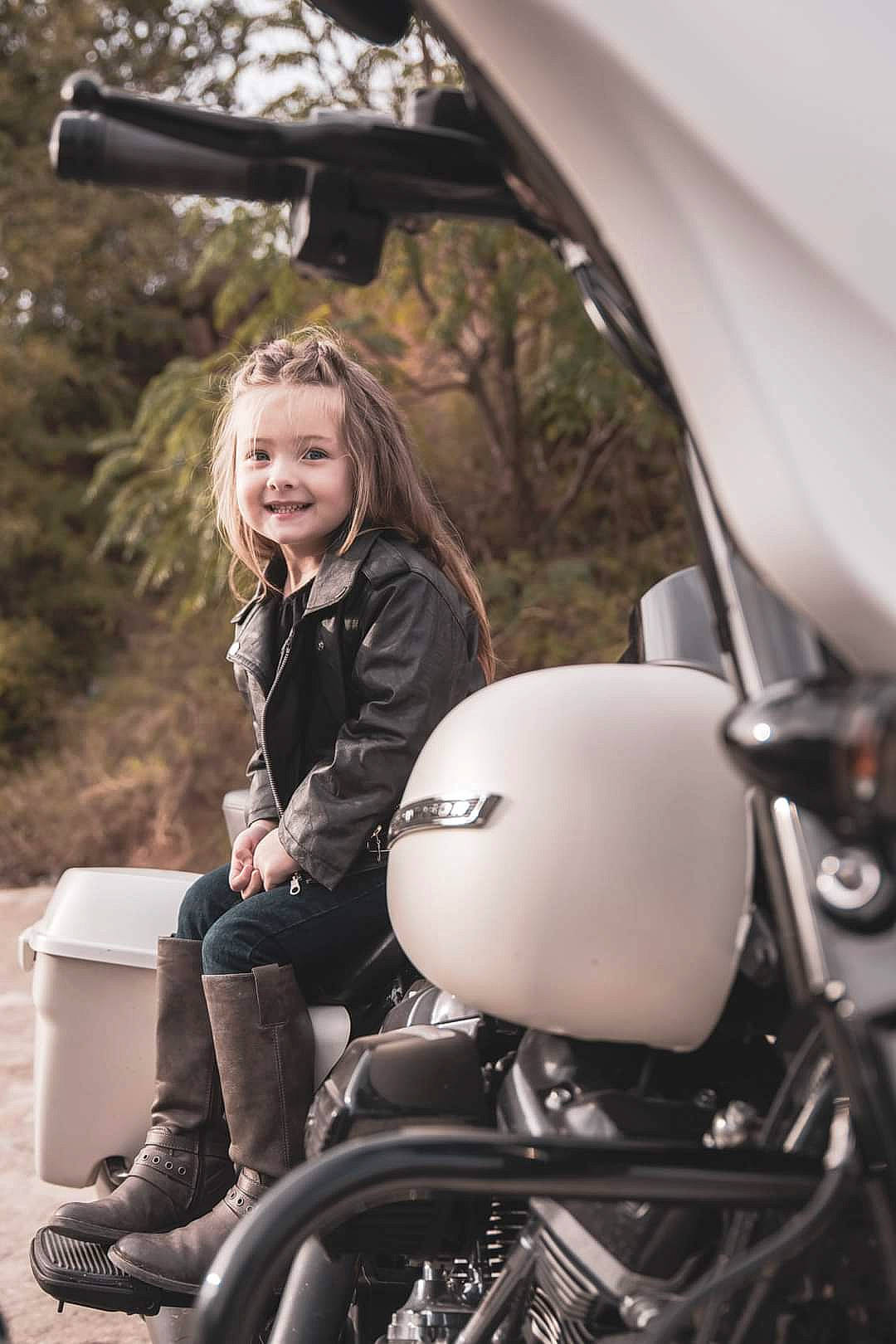 Harley is registered to the contest to win money with this photo: automotive_design, automotive_exterior, automotive_lighting, automotive_tire, black, facial_expression, fender, flash_photography, fuel_tank, hairstyle, happy, headlamp, jacket, joy, motor_vehicle, motorcycle, person, photograph, street_fashion, style