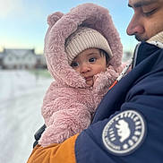 Hira is registered to the contest to win money with this photo: baby, child, adult, winter_clothing, pink_fur, beanie, jacket, snow, outdoor, portrait, holding, cold_weather, face, person, warm_clothing, close_up, family, cute, cozy, daylight
