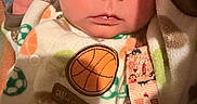 Elijah joined the competition — help win amazing prizes! newborn, baby, infant, child, face, portrait, eyes, wide_eyed, blanket, clothing, onesie, basketball, patterned, cozy, indoors, close_up, head, hand, wrapped, photography