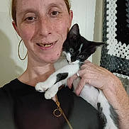 Oreo joined the competition — help win amazing prizes! woman, freckles, hoop_earrings, smiling, kitten, black_and_white_cat, indoor, crocheted_blanket, hand, face, pet, holding, happy, casual_clothing, portrait, cute, animal, domestic, close_up, person
