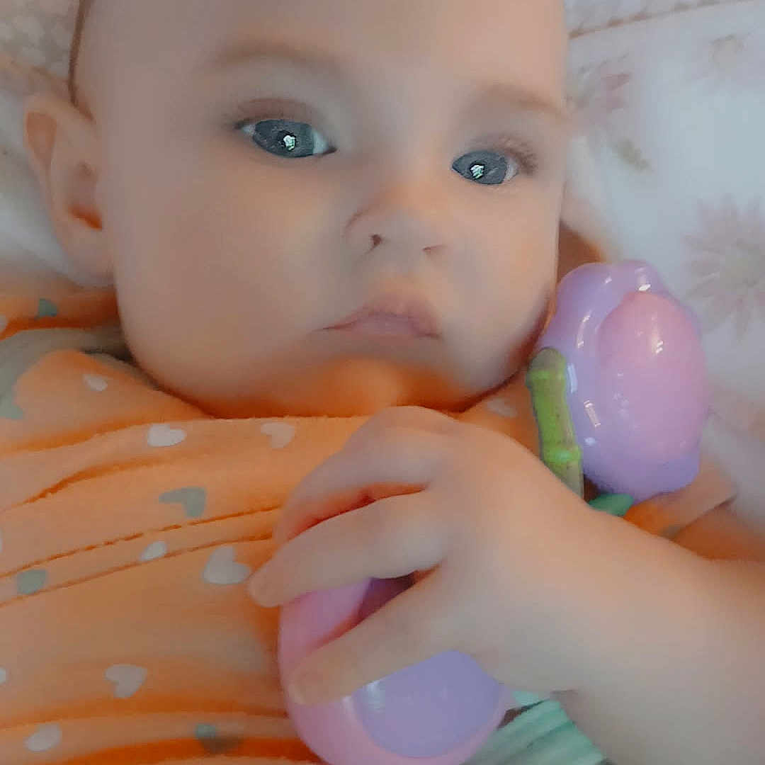 Lana joined the competition — help win amazing prizes! baby, blanket, button, child, closeup, clothing, cute, expressionless, face, hand, indoor, infant, lying_down, orange, person, purple, skin, small_hand, soft, toy