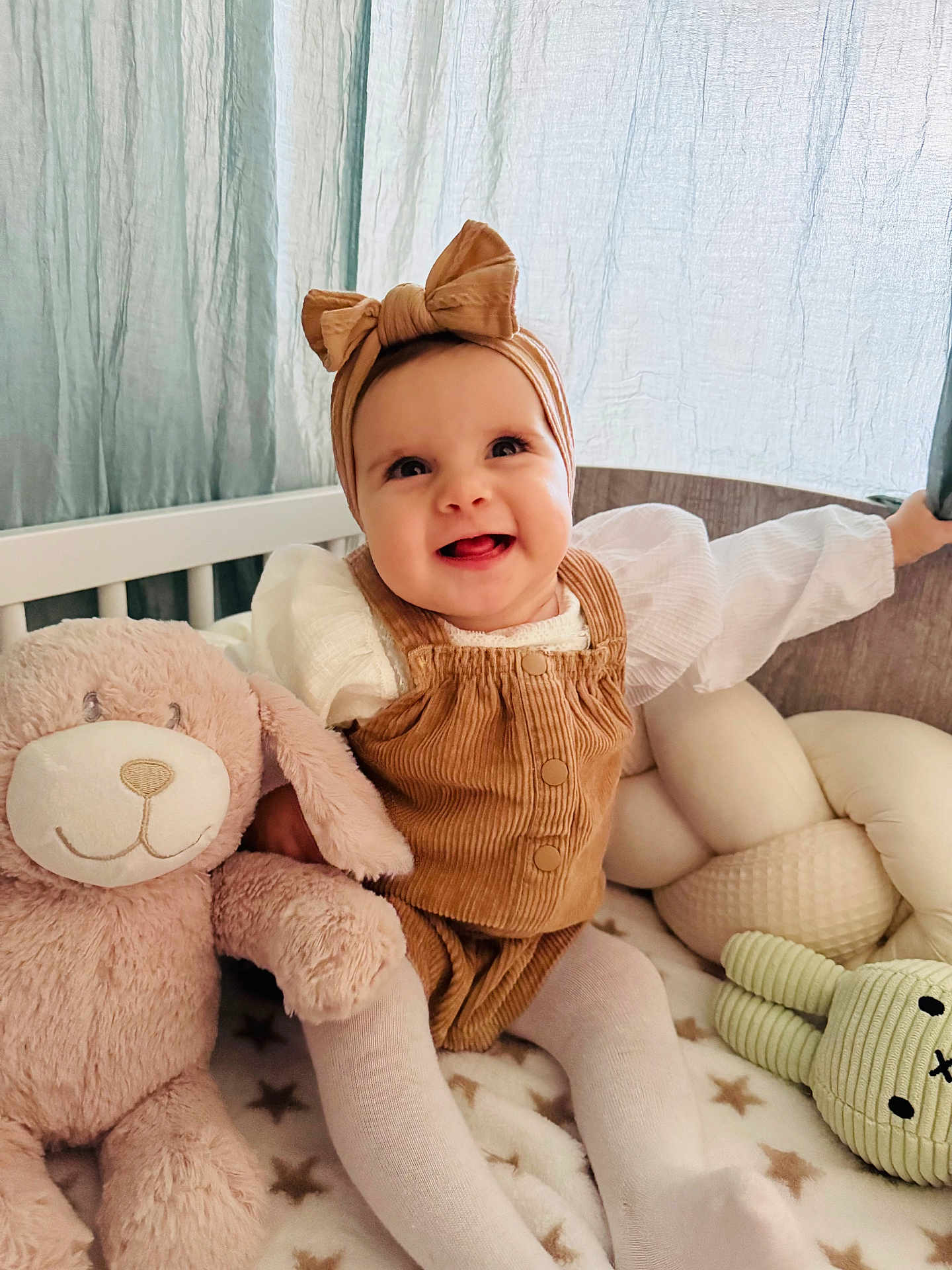 Alma-Maria a rejoint le concours — aidez-le/la à gagner de superbes lots ! baby, child, smiling, headband, bow, corduroy, plush_toy, bunny, crib, blanket, tights, happy, indoors, soft_light, curtains, cute, infant, person, toy, seated