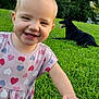 black_dog, child, dog, dress, grass, greenery, hand, happy, hearts, jeans, nature, outdoor, person, pet, playful, smiling, summer, sunlight, toddler, trees
