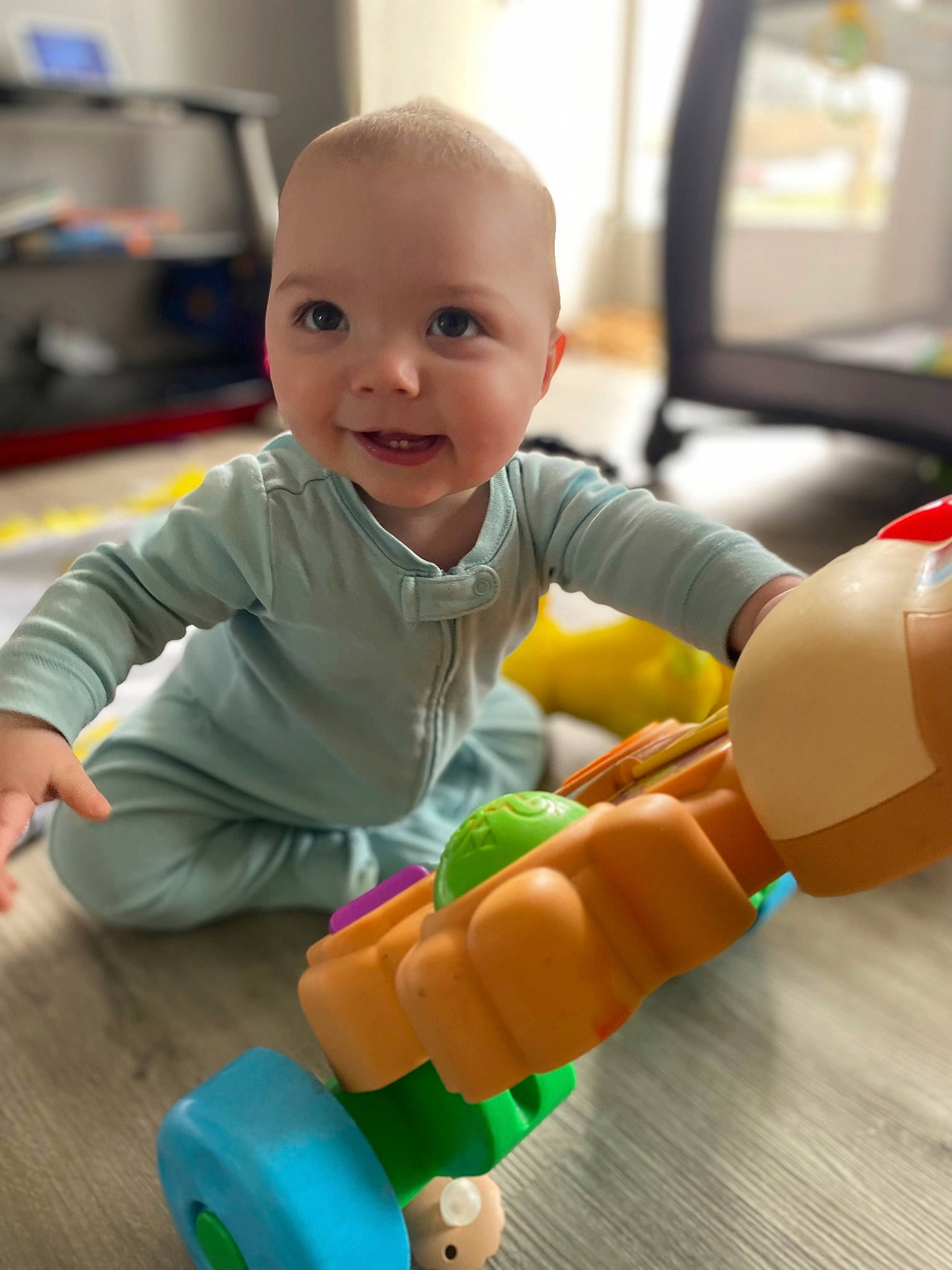 Judah is registered to the contest to win money with this photo: arm, baby_playing_with_toys, baby_toddler_clothing, cheek, facial_expression, finger, hand, happy, head, human_body, orange, organ, person, product, skin, smile, standing, toy, wheel, white