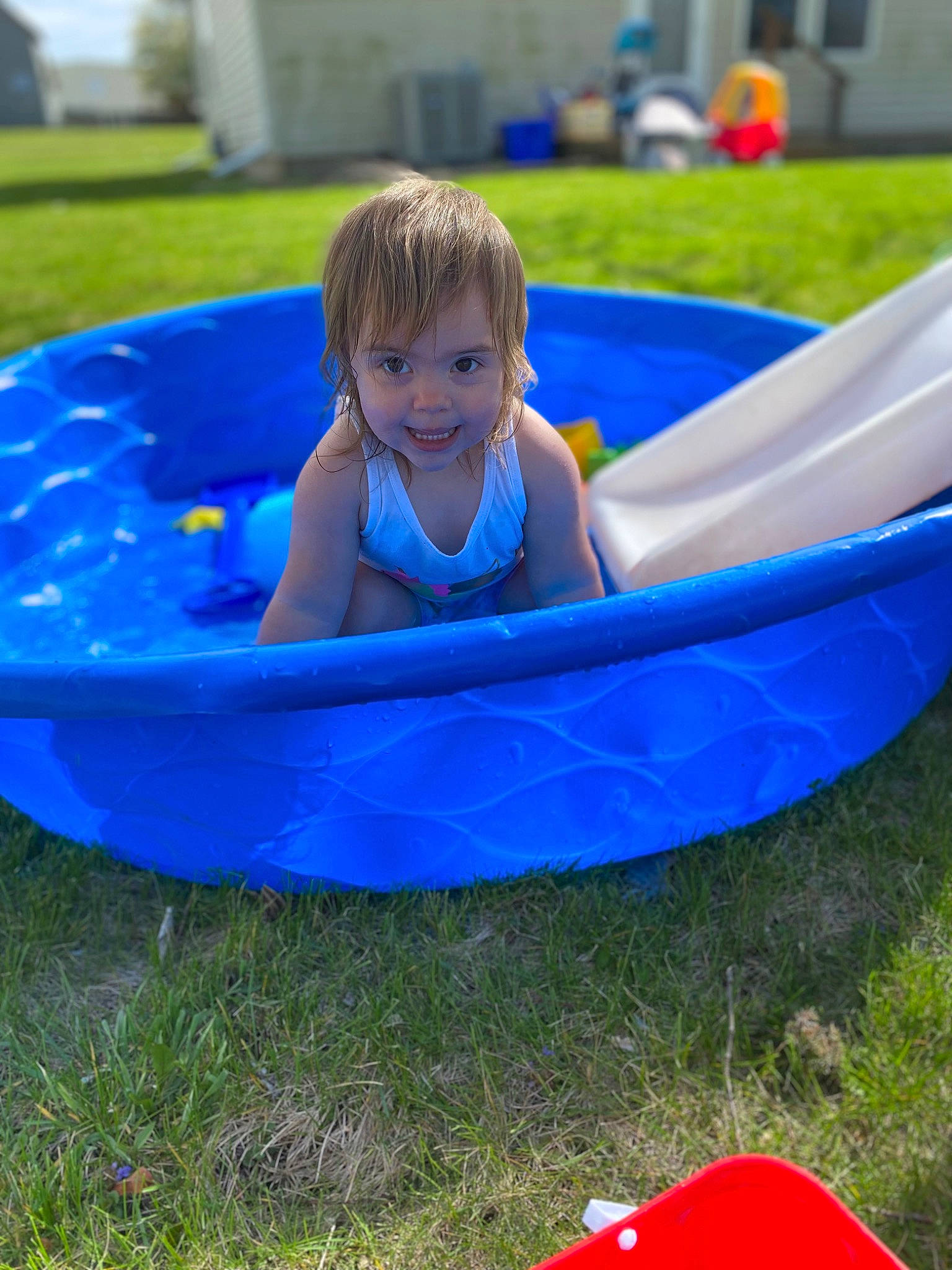 Kaiah is registered to the contest to win money with this photo: automotive_exterior, bathtub, blue, boats_and_boating_equipment_and_supplies, child, electric_blue, fun, games, grass, leisure, nonbuilding_structure, person, plant, plastic, play, recreation, smile, toddler, vehicle, water