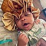 Nymir is registered to the contest to win money with this photo: baby, infant, bonnet, hat, onesie, clothing, face, hand, fist, pacifier, bed, blanket, indoor, floor, door, expression, cute, child, portrait, lying_down