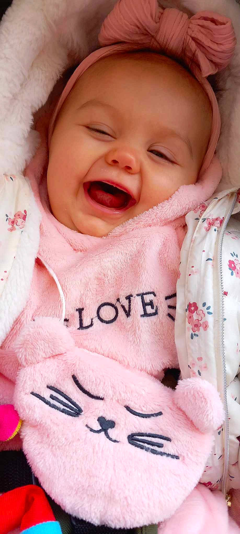 Kelsy a rejoint le concours — aidez-le/la à gagner de superbes lots ! baby, baby_toddler_clothing, cheek, chin, face, facial_expression, gesture, happy, lip, mouth, neck, nose, outerwear, person, photograph, pink, skin, sleeve, smile, textile